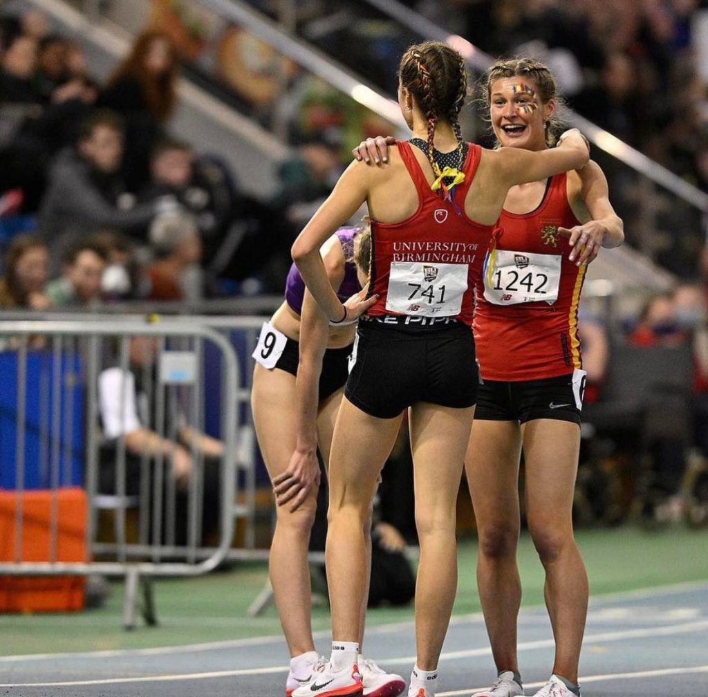 Two female University of Birmingham athletes hugging and smiling after their race