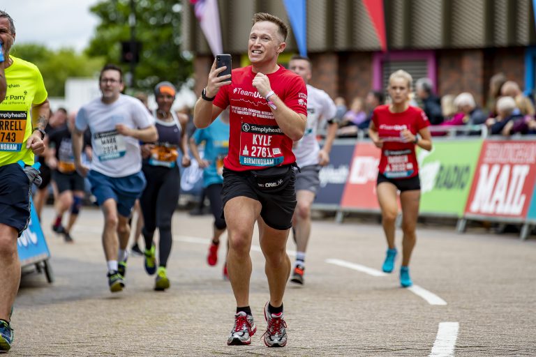 Male runner recording his run on his phone at the Great Birmingham Run 10k