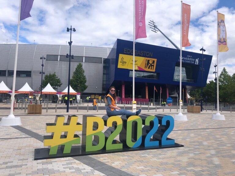 Volunteer Becki sits on giant letters spelling #B2022