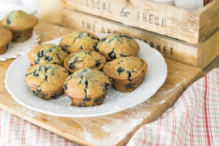 7 blueberry muffins on a plate dusted with icing sugar