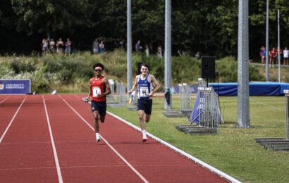 2 men running towards finish line- one from UOB