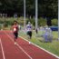 2 men running towards finish line- one from UOB