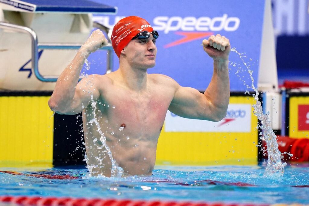 Oliver (Ollie) Morgan cheering with arms up in the air in the pool.