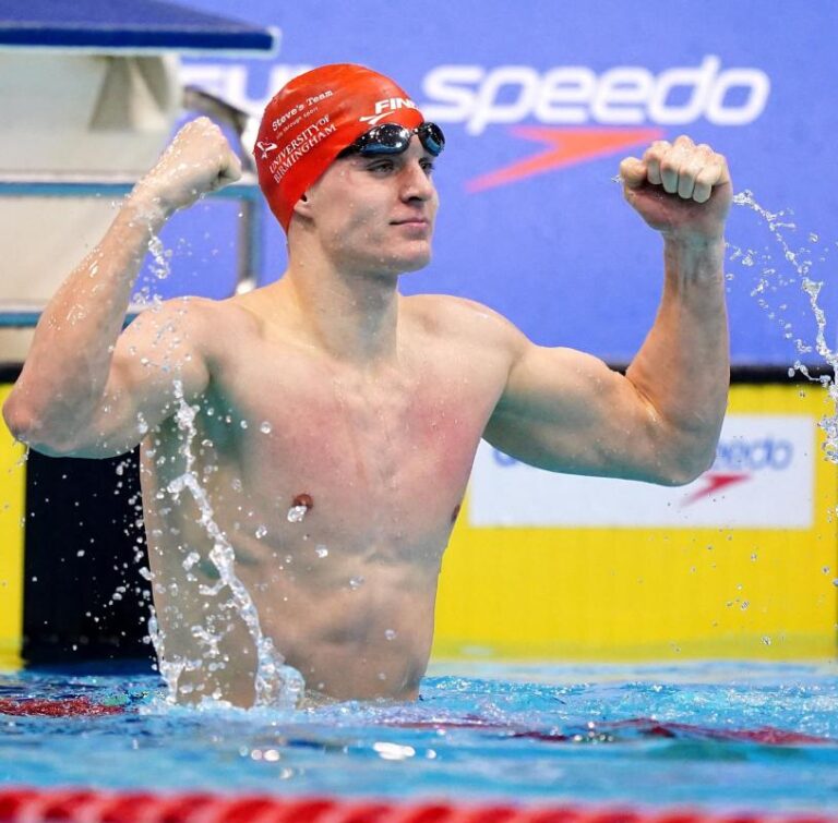 Oliver (Ollie) Morgan cheering with arms up in the air in the pool.