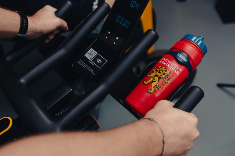 UB Sport branded water bottle in bottle holder on exercise bike