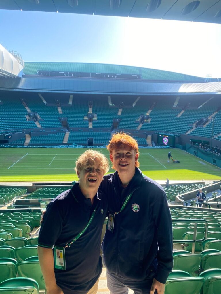 Two tennis students standing in front of spectator seats