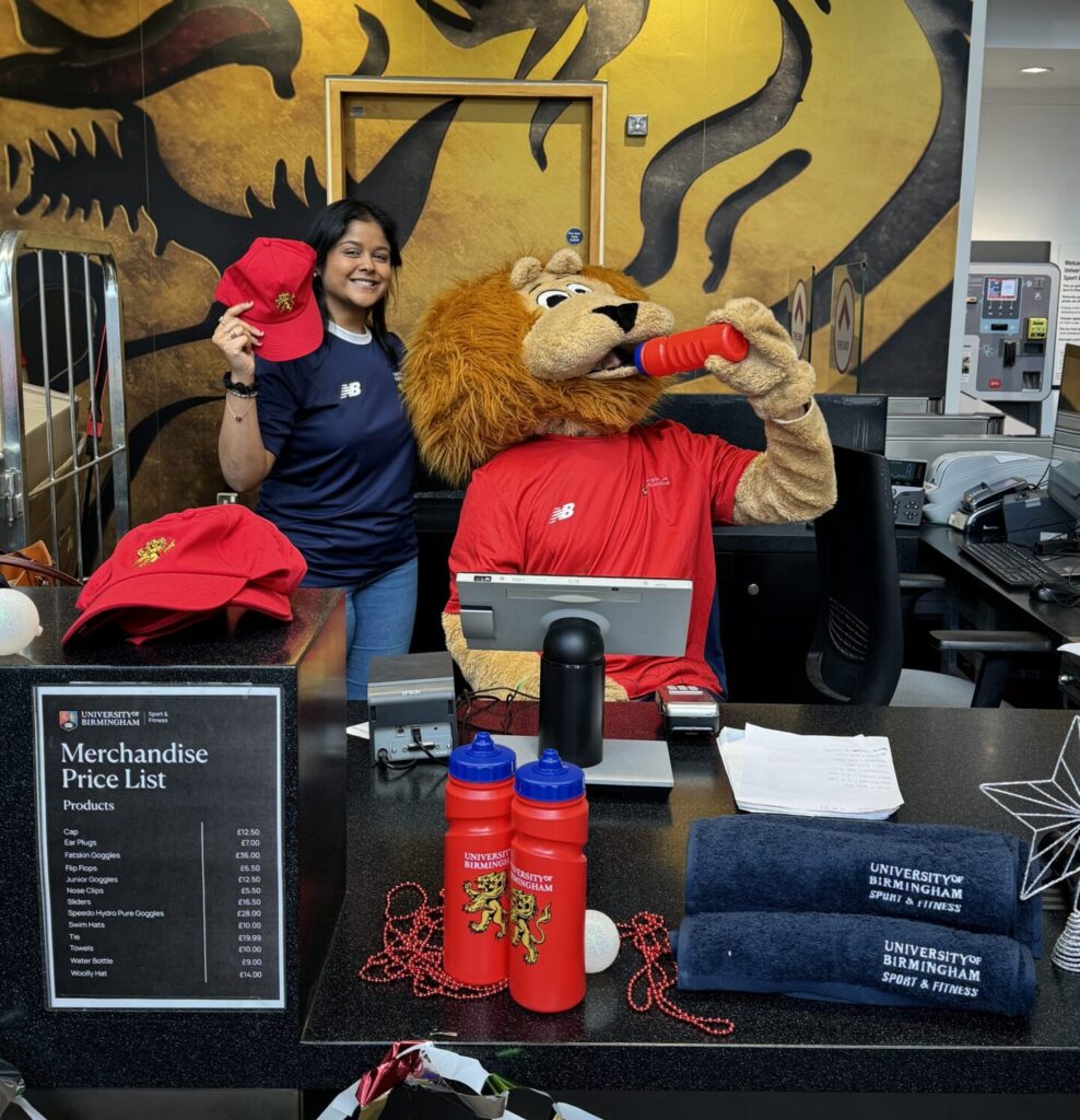 Sales ambassador selling merch with Rory mascot at BUCS desk