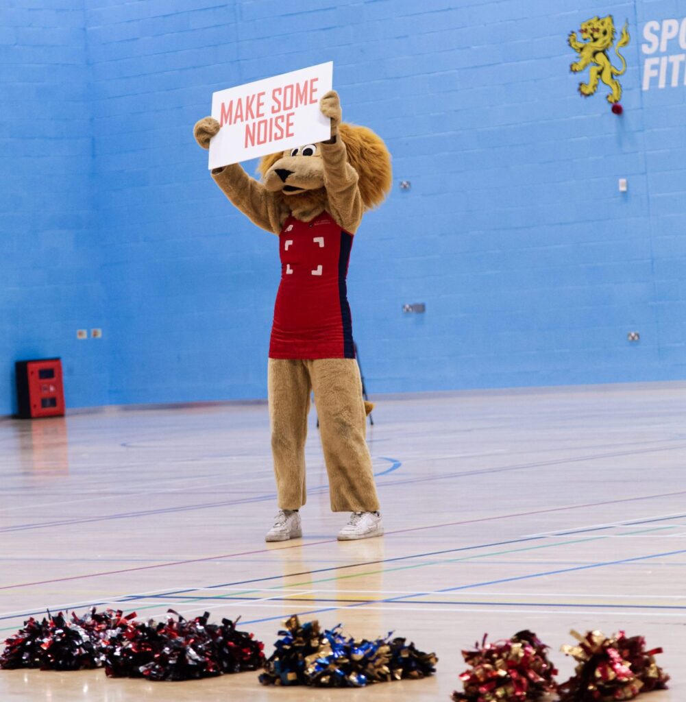 Rory Holding up 'go Lions' sign at Netball Super Series event, intercept