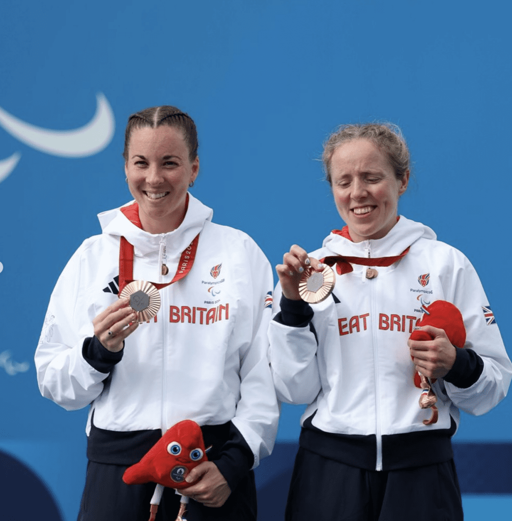 Lora Fachie holding bronze medal with fellow para-athlete