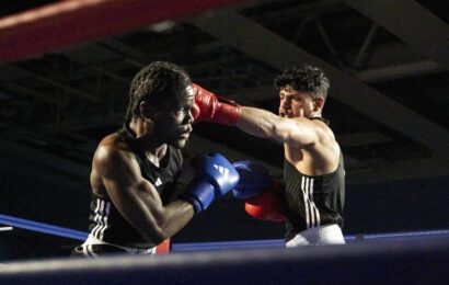 Two boxers in the ring with one reaching out to punch the other.