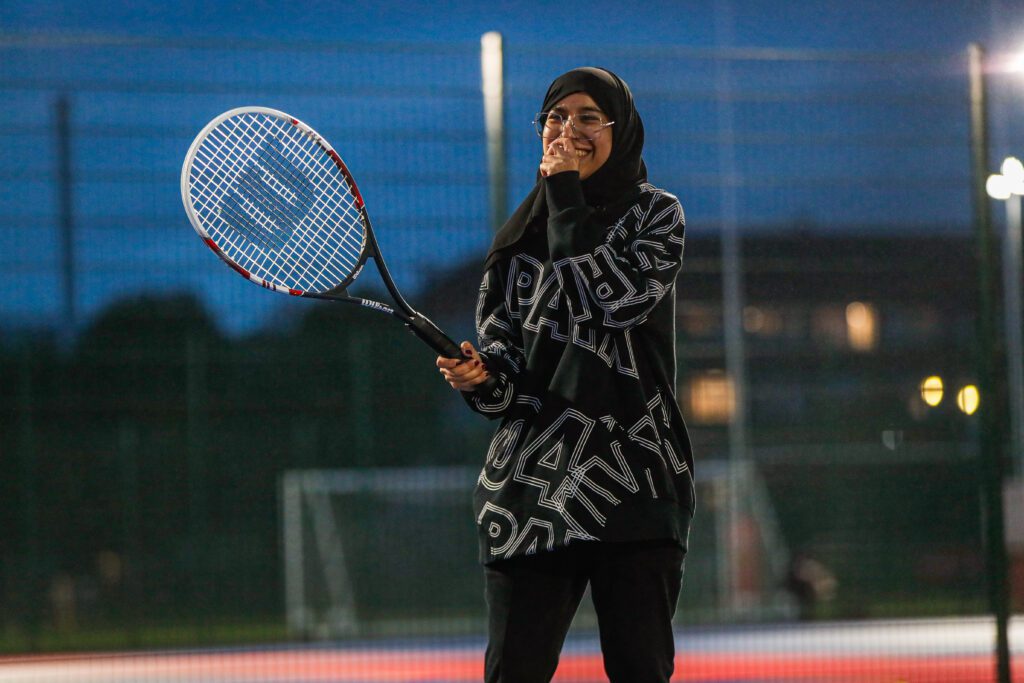 Active Residences student in Hijab holding raquet on tennis court