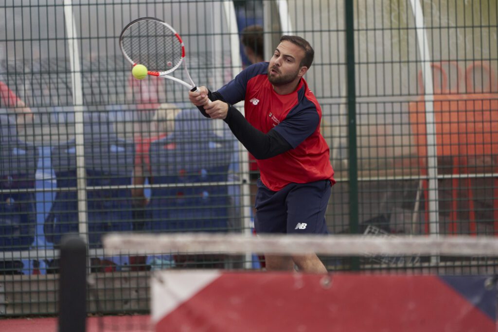 Male student playing tennis on court