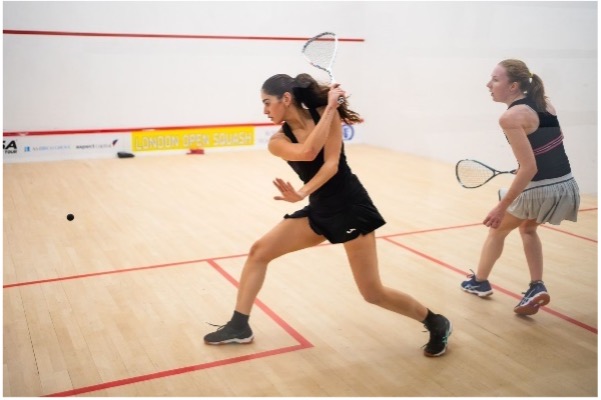 Hana Ismail swinging raquet in Squash court