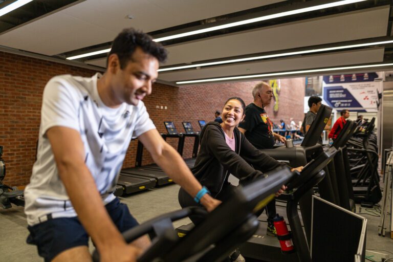 Man and woman on a bike in the gym, smiling